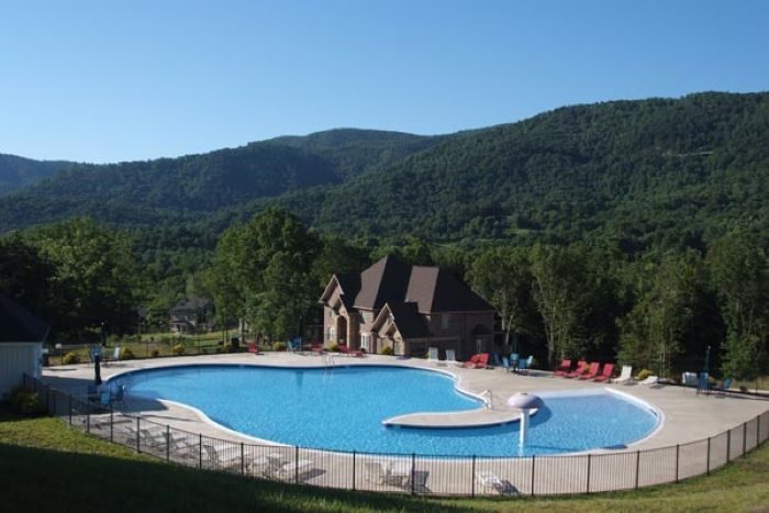 The community pool with the clubhouse and green mountains behind it